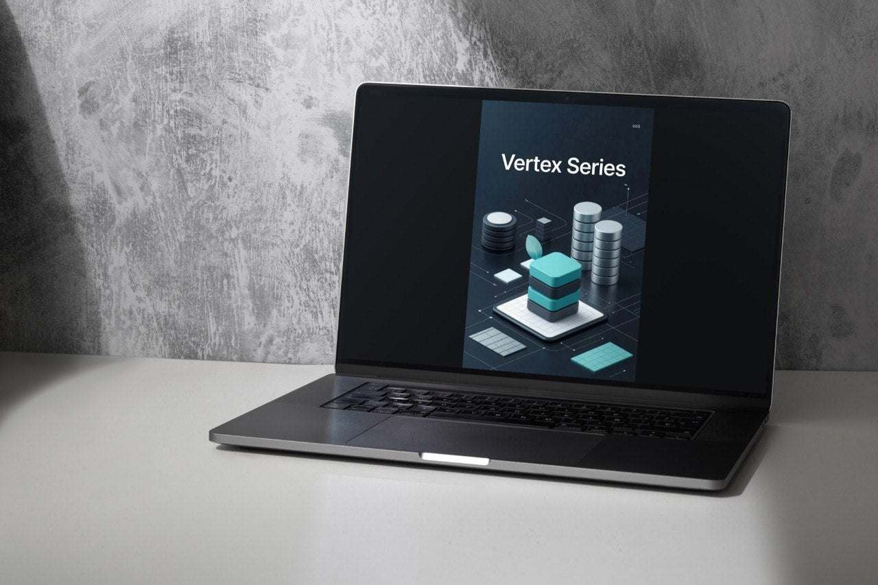 Laptop displaying 'Vertex Series' on a gray surface with a concrete wall background